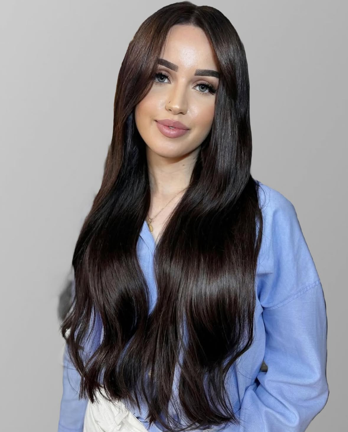 Een professionele haarstylist van Annas Hairextensions is bezig met het inzetten van haarextensies bij een tevreden klant. De stylist werkt zorgvuldig en met aandacht voor detail, terwijl de klant in de spiegel kijkt en glimlacht. De haarextensies zijn van hoge kwaliteit en voegen lengte en volume toe aan het haar, waardoor de klant er stralend uitziet. De salon heeft een moderne en uitnodigende sfeer, met een focus op persoonlijke service en vakmanschap.